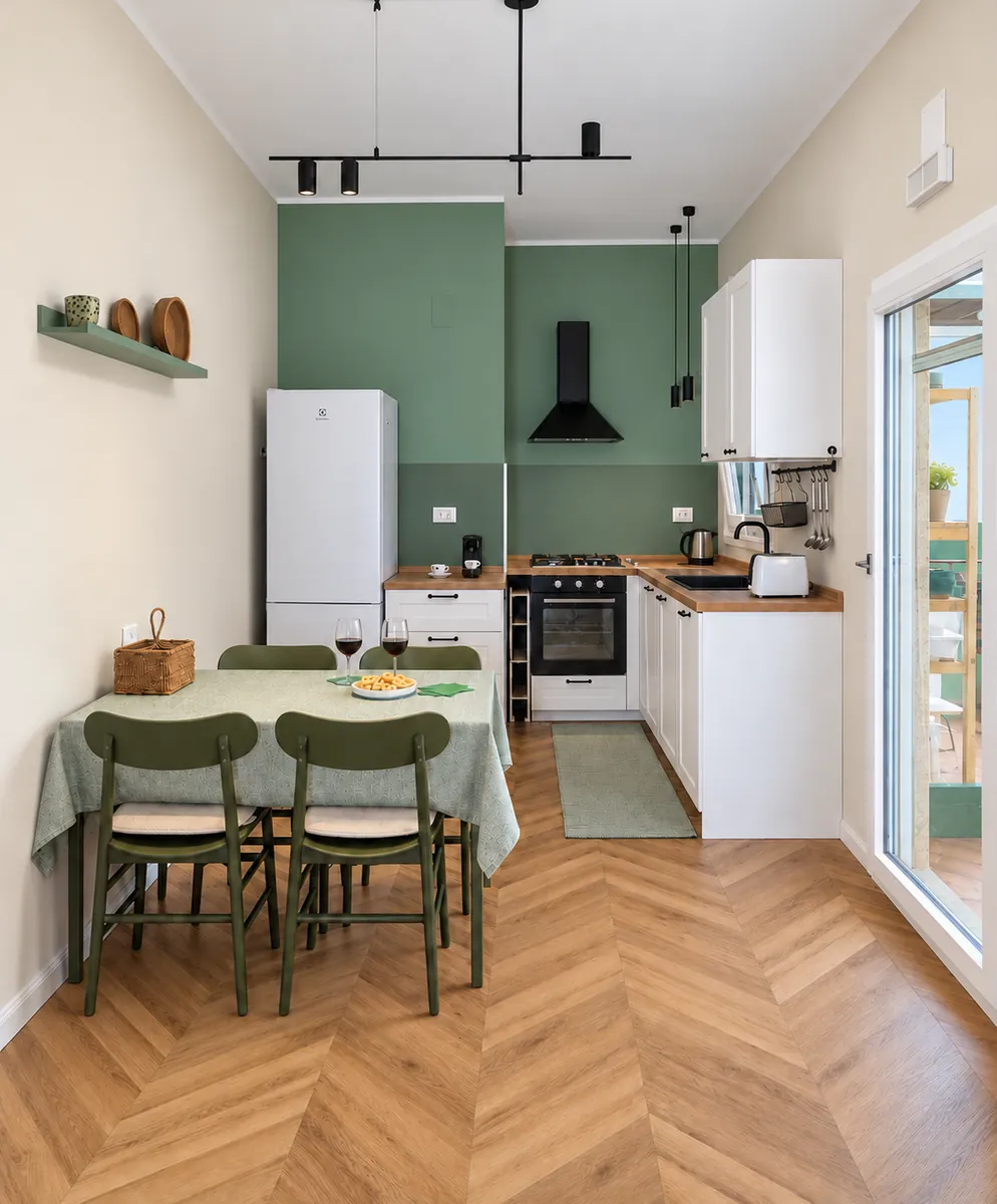 Kitchen of BDS House with sage green walls and a dining table for six