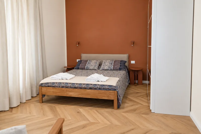 Double bedroom with terracotta wall, oak bed and morning light through linen curtains