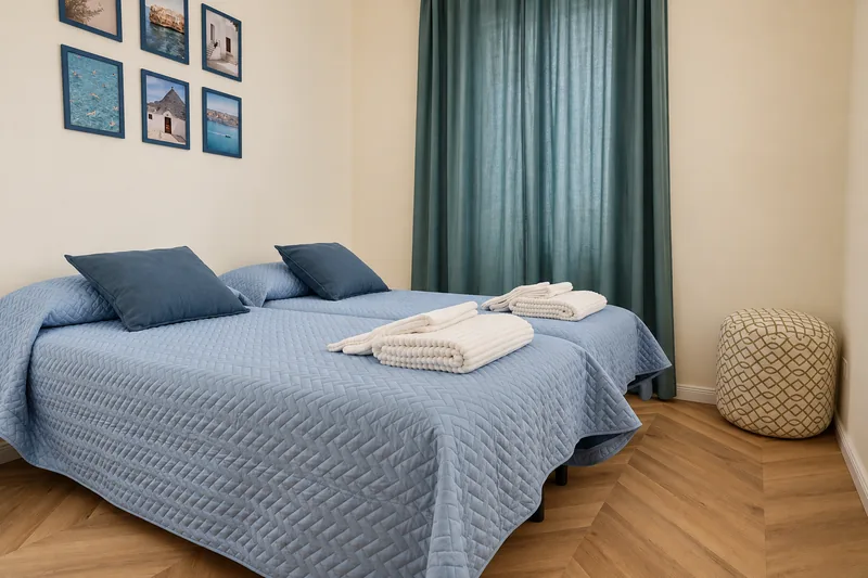 Twin bedroom with two single beds that can be joined, blue bedspreads and teal curtains