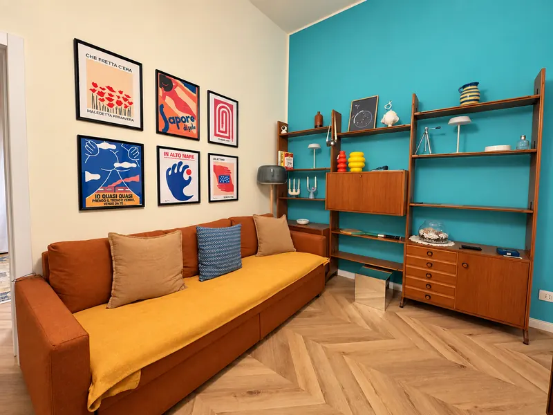 Living room with terracotta sofa bed, 1960s teak bookcase and turquoise wall, BDS House Brindisi